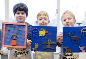 Drie jongens laten hun lego-zetsels zien.